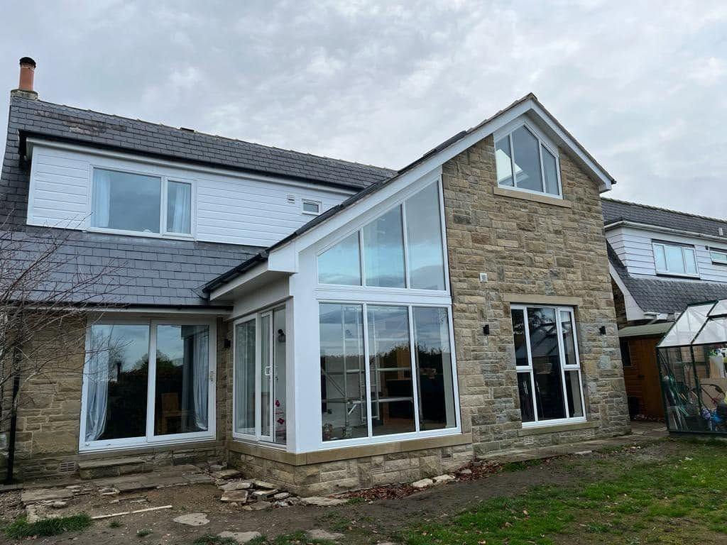 Stone two-storey extension with a full-height glazed gable